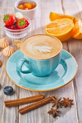 Blue cup of cappuccino with cinnamon on wooden background.