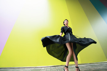 Fashion woman. Young beautiful chinese girl dancing outdoor wearing long black dress with high...