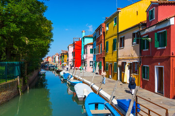 Fototapeta na wymiar ITALY, BURANO - SEPTEMBER 26, 2017: Colourful houses along the canal on the island of Burano.The island is a popular attraction for tourists due to its picturesque architecture