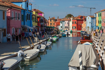 Fototapeta na wymiar ITALY, BURANO - SEPTEMBER 26, 2017: Tourists walk along canals and colorful houses in Burano