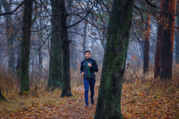 Obraz premium Young man jogging in autumn park in the morning