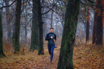 Obraz premium Young man jogging in autumn park in the morning