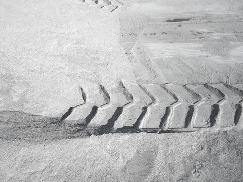 The prints of tractor tire on white sand at the factory. Background, copy space