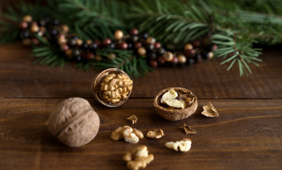 Obraz na płótnie Canvas Christmas healthy background, walnuts, shell, fir tree branch and colorful bead balls Christmas decoration on rustic wooden table. Empty space for text, New Year winter theme layout concept.