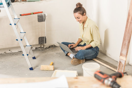 High Angle View Of Smiling Young Woman Using Laptop While Sitting On Floor At New House