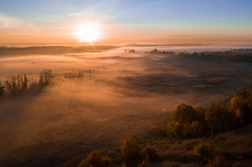 Deep thick fog in the valley. Long shadows from the trees. Atmospheric beautiful dawn. Aerial drone...