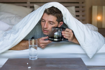lifestyle home portrait of young exhausted and wasted man waking up suffering headache and hangover...