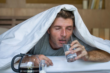 lifestyle home portrait of young exhausted and wasted man waking up suffering headache and hangover...