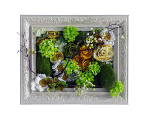 Artificial flowers in a picture frame on a white background.
