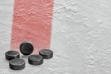 Fototapeta premium Pucks and ice rink fragment with a red line