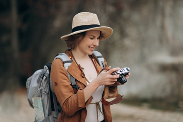 Active healthy Caucasian woman taking pictures with an vintage film camera on a forest rocks