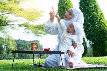 Asian Muslim mother and her son enjoying quality time at park, Mom and son pointing their finger, Muslim mom and son concept