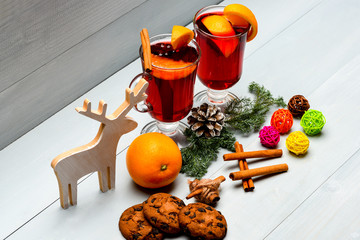 Winter beverage concept. Glasses with mulled wine or hot drink near wooden deer decoration on white...