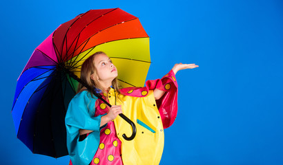 Enjoy rainy weather with proper garments. Waterproof accessories make rainy day cheerful and pleasant. Kid girl happy hold colorful umbrella wear waterproof cloak. Waterproof accessories for children