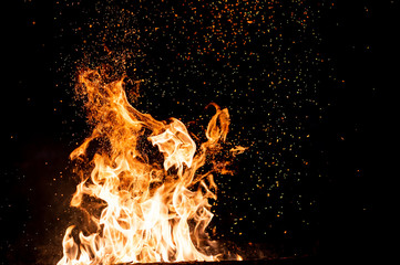 Burning woods with firesparks, flame and smoke. Strange weird odd elemental fiery figures on black background. Coal and ash. Abstract shapes at night. Bonfire outdoor on nature. Strenght of element.