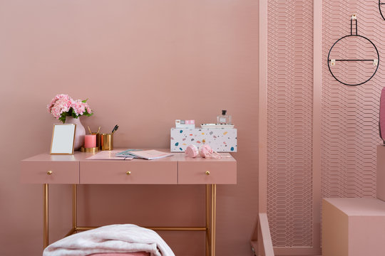 Working corner with white and multicolor pebbles terazzo cabinet on baby pink working top with old rose painted wall in the background / interior design concept / interior for advertising