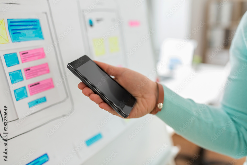 Aufkleber technology, user interface design and people concept - hand of ui designer or developer holding smar