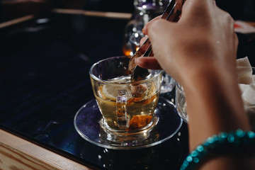 girl puts sugar in a glass Cup of tea.