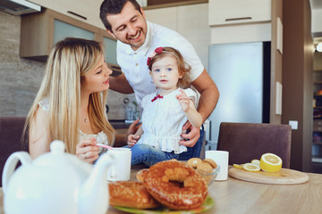 A happy family in the kitchen while sitting at a table.