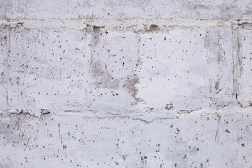 wall of concrete blocks with whitewashing with potholes, cracks and stains, shot on a cloudy autumn day
