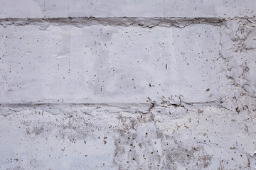 wall of concrete blocks with whitewashing with potholes, cracks and stains, shot on a cloudy autumn day