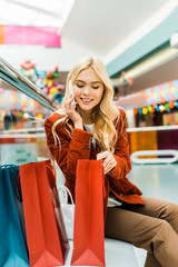attractive woman talking on smartphone and looking into shopping bags