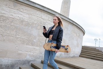 Girl texting while walking with a skate board