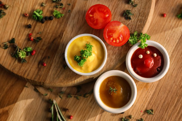 Different tasty sauces in bowls on wooden boards