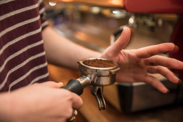 Barista holding portafilter and coffee tamper making an espresso coffee