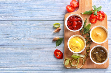 Different tasty sauces in bowls on light wooden table