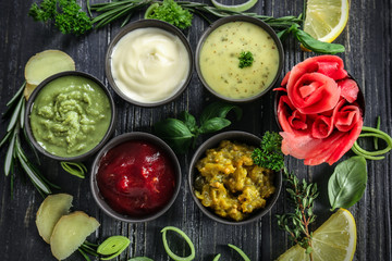 Tasty sauces with marinated ginger and herbs on wooden table