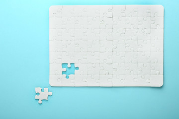 White jigsaw puzzle with piece on color background