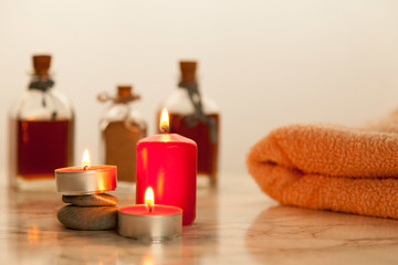 Plakat burning red candles and bath oils on marble