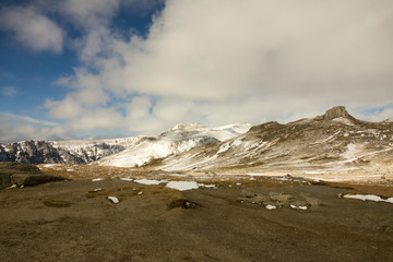 First snow on the mountains, in november, late autumn, blue sky with grey clouds
