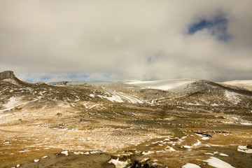 First snow on the mountains, in november, late autumn, blue sky with grey clouds
