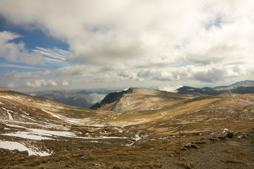 First snow on the mountains, in november, late autumn, blue sky with grey clouds
