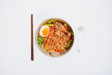 Hot and Spicy noodle in bowl and ingredients on isolated white background, Korea noodles with boil eggs in bowl with spoon and chopsticks, copy space and top view