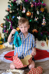 Young boy pulling a funny face looking at an unwanted Christmas present