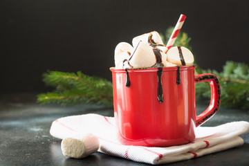 Mug of hot chocolate and cacao with marshmallows with christmas tree branches on black board. Xmas holiday.