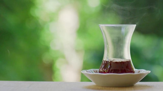 Slow motion shot of preparing Turkish tea in a garden with green background surrounded with trees. 