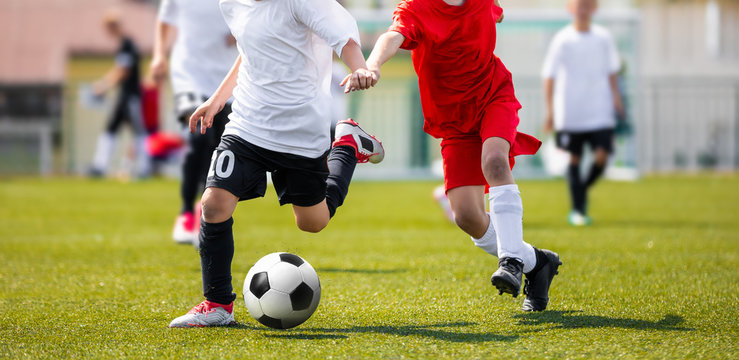 Two Young Boys in Soccer Sportswear Running and Kicking Ball on the Field. Low Angle Image of Youth Football Competition with Blurred Background