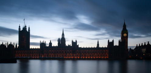 Fototapeta na wymiar London, UK - Intentionally under-exposed panoramic view of The Houses of Parliament and the Big Ben silhouetted against sky at dusk. Long exposure shot.