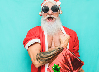 Tattoo fit Santa Clause with gift box wearing funny fest sunglasses - obrazy, fototapety, plakaty