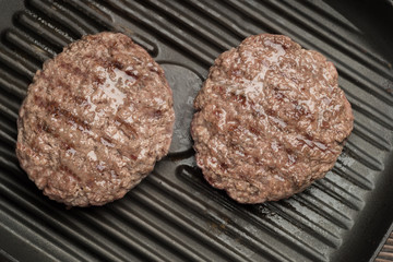 Food: fried homemade burger on a frying pan.