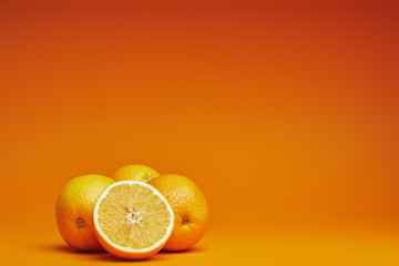 close-up view of fresh ripe whole and sliced oranges on orange background