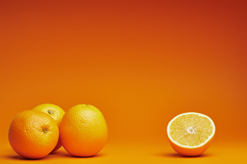 close-up view of whole and halved oranges on orange background