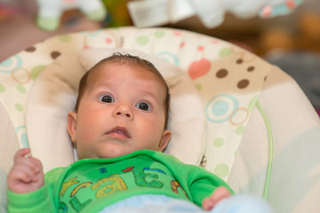 The newborn lies on swing automatic electrical chair and enjoys it