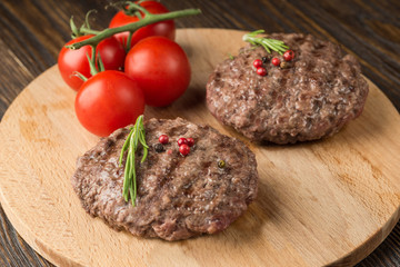Freshly grilled burger meat ion wooden cutting board.