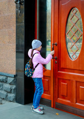 A little girl opens an old beautiful door.