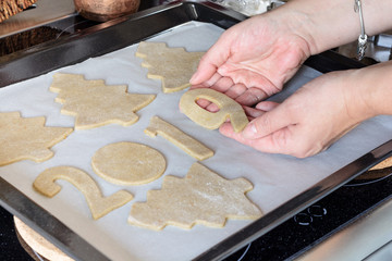 Making Christmas gingerbread at home, shapes from dough are cutted with cutters, such as trees,...